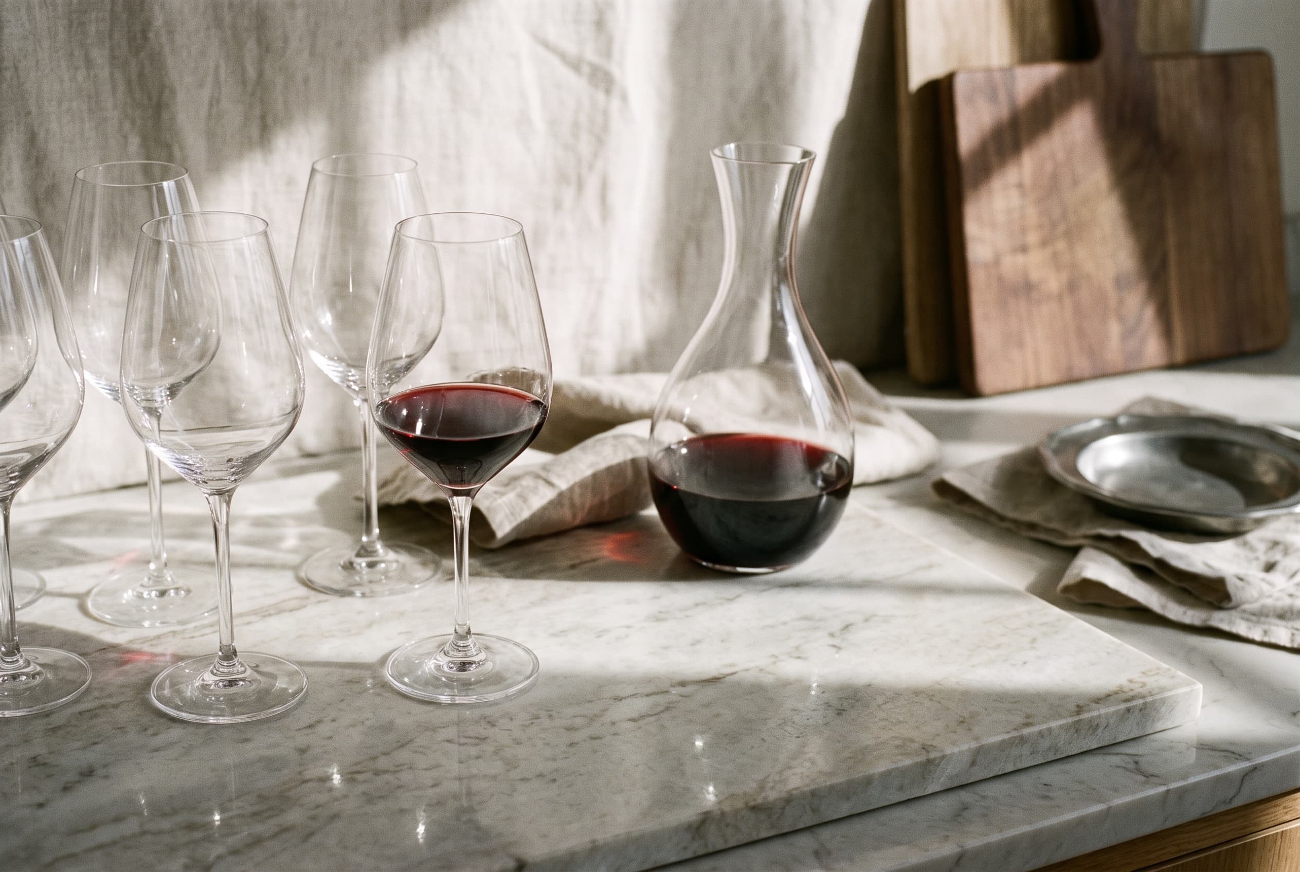 Crystal wine glasses and a decanter on a marble counter in window light